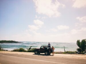 In this picture you can see the sea of Cozumel, a jeep and 2 people exploring the island